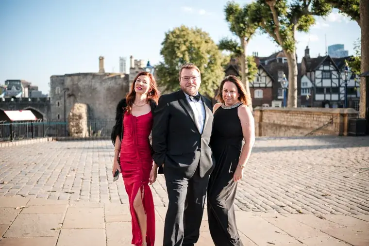 Three guests posing in the sunlit courtyard at the Chambers High Net Worth Awards 2025.