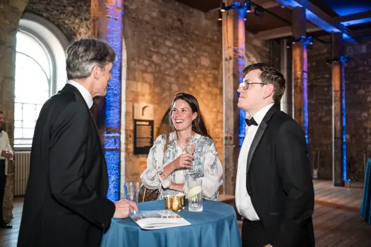 Three guests sharing a conversation at a tall reception table at the Chambers High Net Worth Awards 2025.