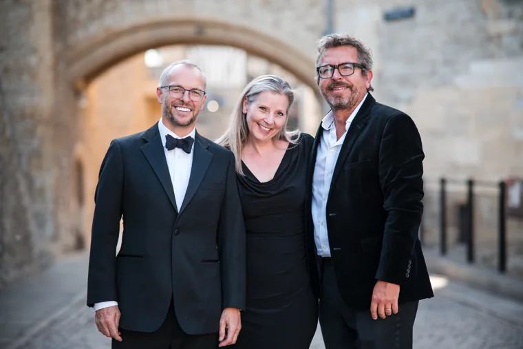 Three smiling guests posing beneath the stone archway at the Chambers High Net Worth Awards 2025.