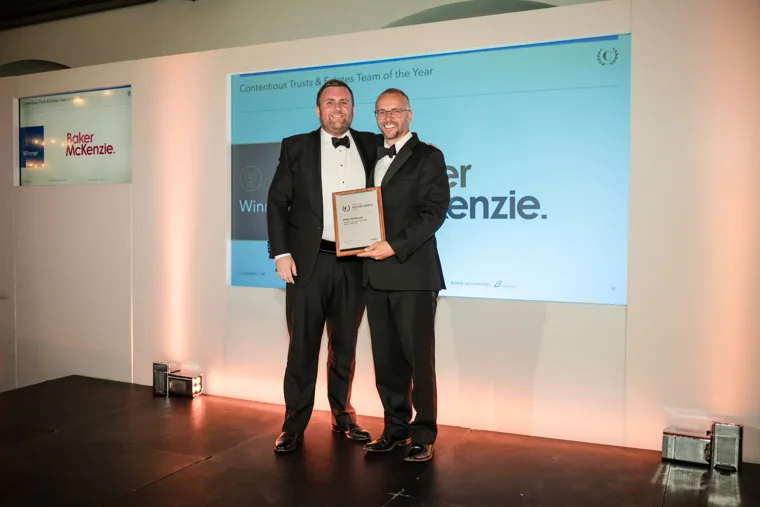 Two award recipients holding their certificate on stage at the Chambers High Net Worth Awards 2025.