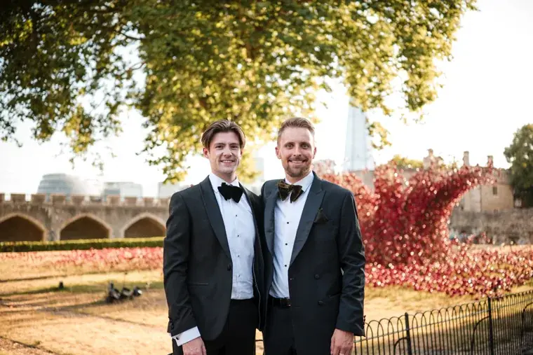 Two guests in dinner jackets posing beside the poppy installation at the Chambers High Net Worth Awards 2025.