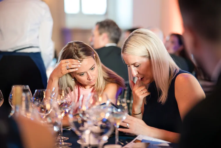 Two guests leaning together in conversation during dinner at the Chambers High Net Worth Awards 2025.