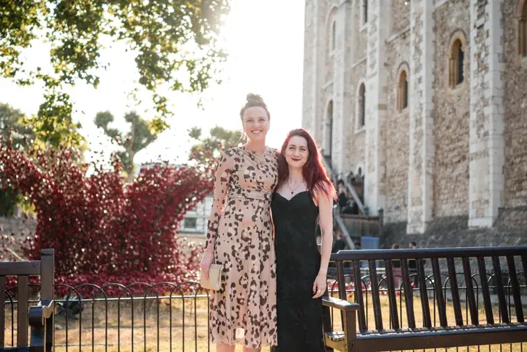 Two guests posing beside the red poppy installation at the Chambers High Net Worth Awards 2025.