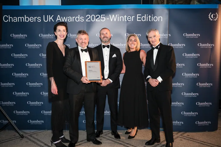 A group celebrating with a framed award at the Chambers UK Awards winter edition.