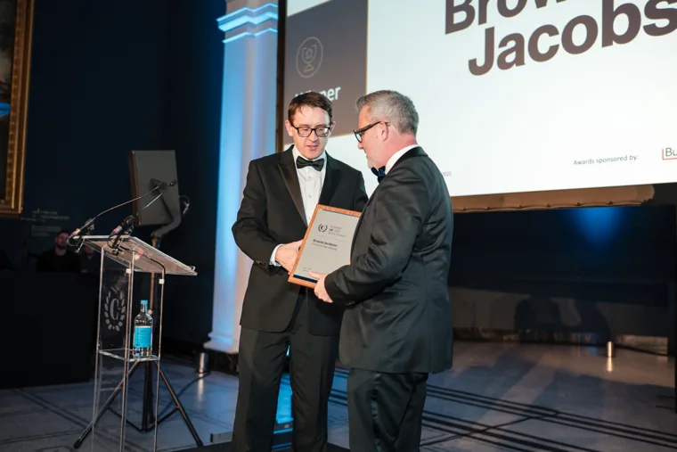 A presenter handing over an award on stage at the Chambers UK Awards winter edition.