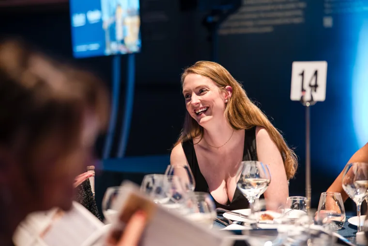 A woman smiling during a dinner conversation at the Chambers UK Awards winter edition.
