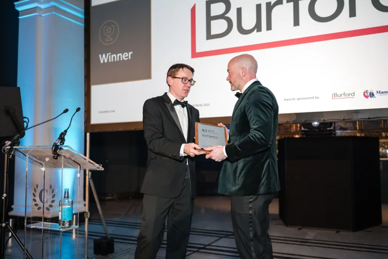 An award recipient shaking hands on stage at the Chambers UK Awards winter edition.