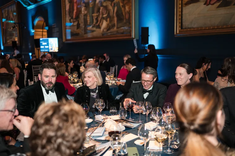 Guests smiling together around a dinner table at the Chambers UK Awards winter edition.