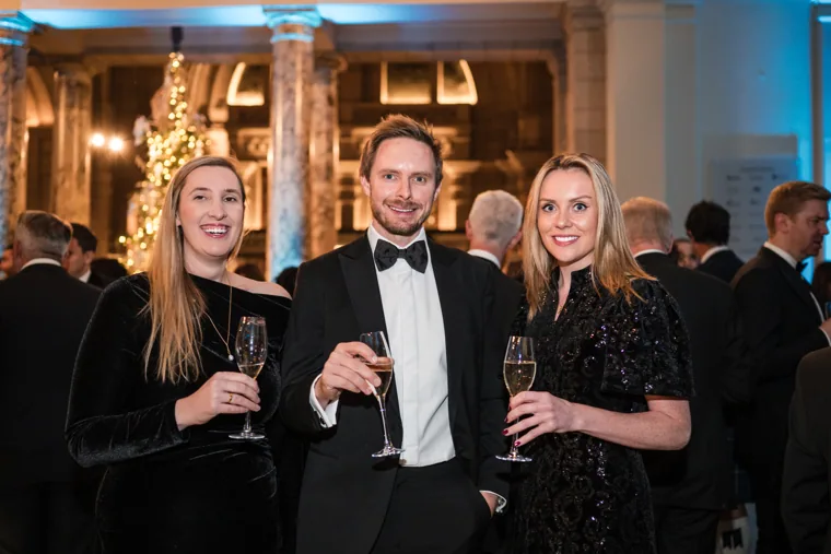 Three guests smiling with drinks at the Chambers UK Awards winter edition.