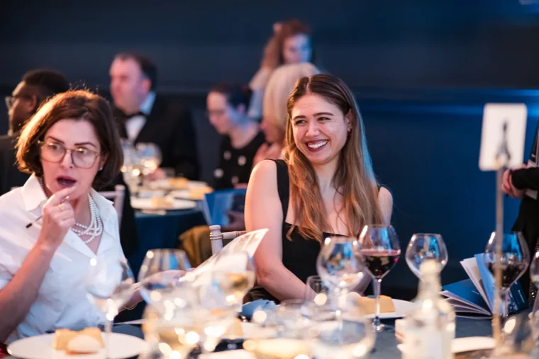 Two women smiling at their dinner table at the Chambers UK Awards winter edition.