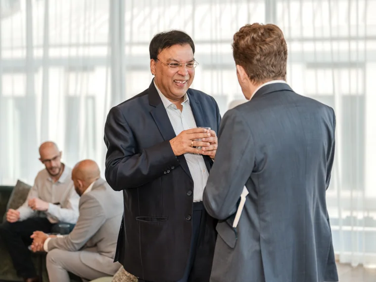 Two guests talking beside the venue windows at the Goodwin networking event.