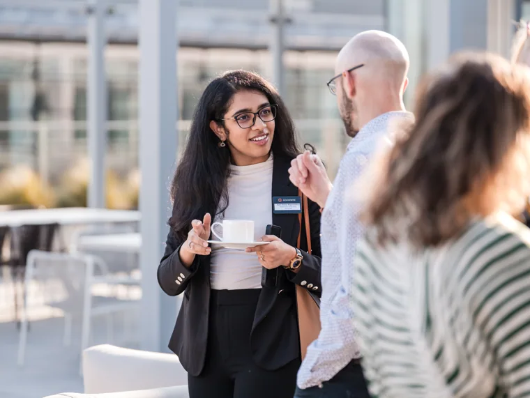 An attendee listening during a reception conversation at the Goodwin networking event.