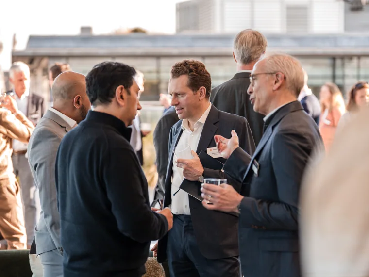 A group talking beside the terrace doors at the Goodwin networking event.