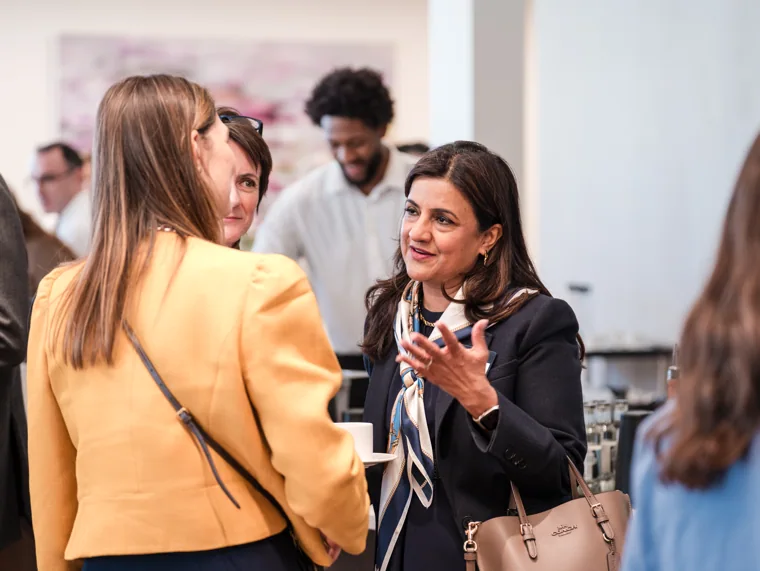 A guest gesturing during an animated conversation at the Goodwin networking event.