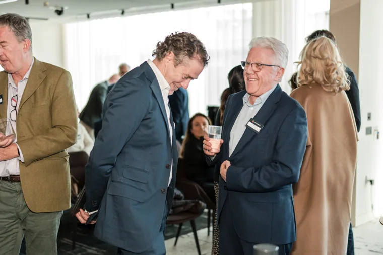 Guests in a lively indoor conversation at the Goodwin networking event.