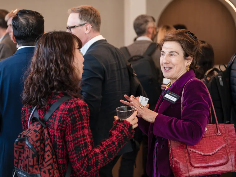 A guest making an animated gesture during conversation at the Goodwin networking event.