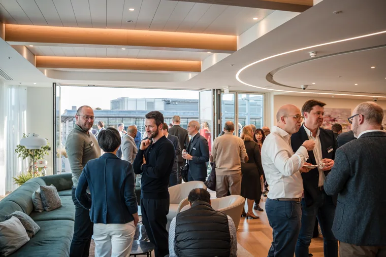 Attendees in conversation beside the reception area at the Goodwin networking event.