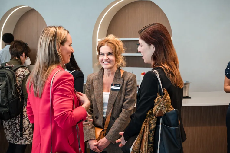 Three guests laughing together during the reception at the Goodwin networking event.