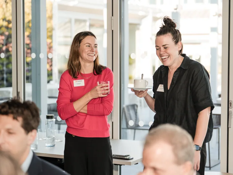 Two guests sharing a laugh in the networking space at the Goodwin networking event.