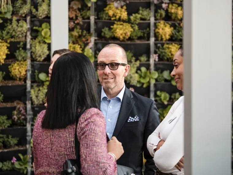 Guests talking beside the planted wall at the Goodwin networking event.