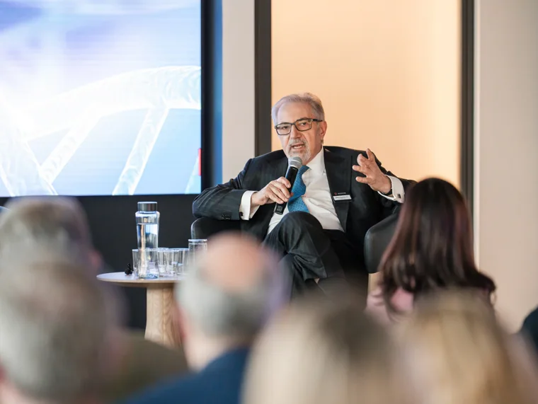 A speaker addressing attendees with a microphone at the Goodwin networking event.