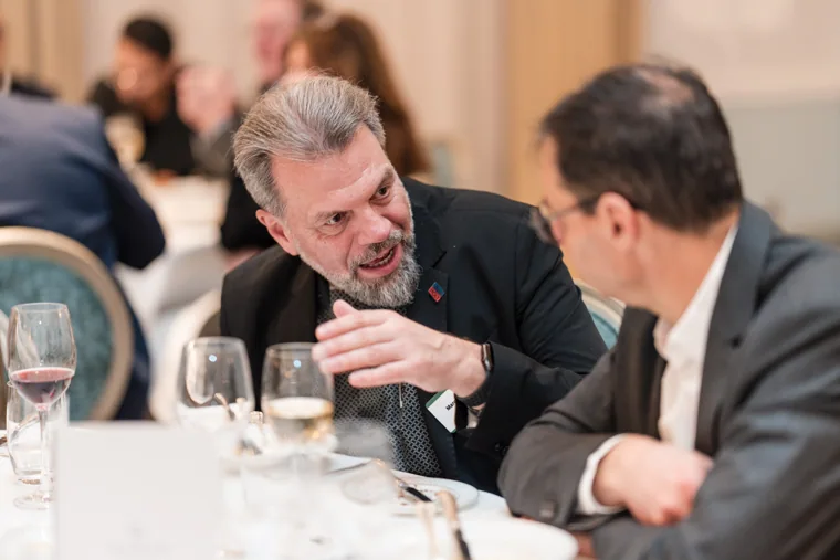 A guest leaning forward in conversation at dinner at the S-OIL European customer dinner.