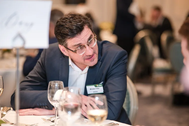 A guest leaning into a conversation at dinner at the S-OIL European customer dinner.
