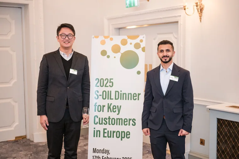 A guest posing beside the event sign at the S-OIL European customer dinner.