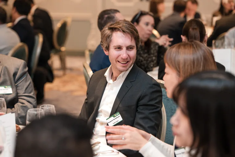 A guest smiling across the dinner table at the S-OIL European customer dinner.