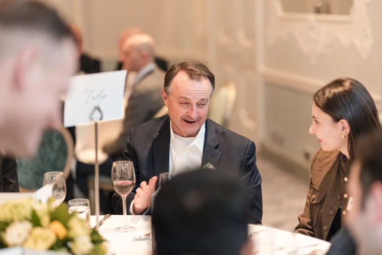 A guest smiling while speaking across the table at the S-OIL European customer dinner.