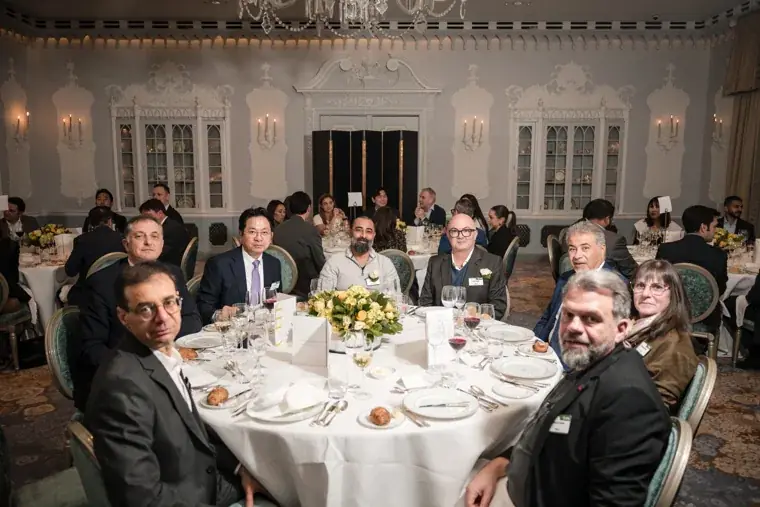 A table of guests posing together at dinner at the S-OIL European customer dinner.