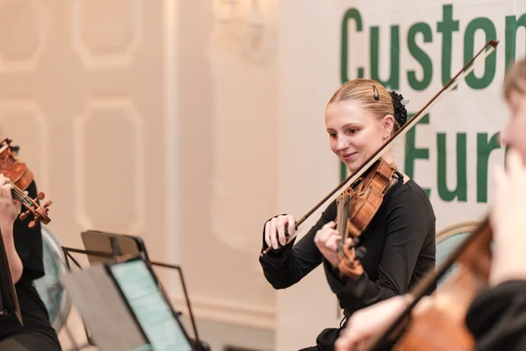A violinist framed against the event backdrop at the S-OIL European customer dinner.