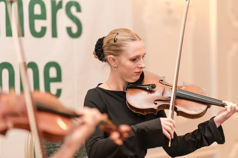 A violinist performing beside the S-OIL sign at the S-OIL European customer dinner.