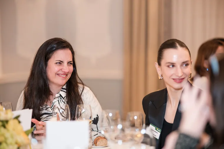 A woman in a patterned jacket smiling across the dinner table at the S-OIL European customer dinner.