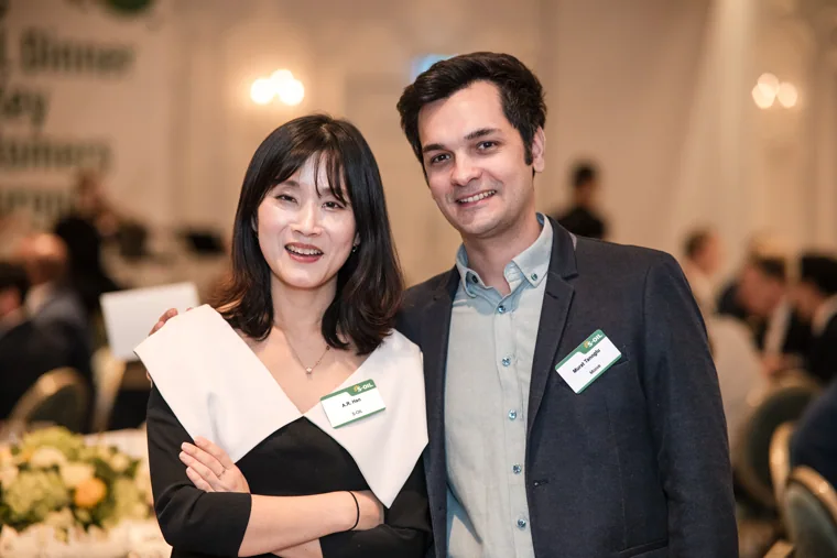 A woman in black and white posing with a colleague at dinner at the S-OIL European customer dinner.