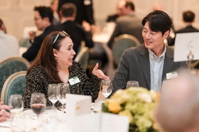 A woman speaking with a guest across the table at the S-OIL European customer dinner.