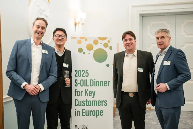 Four guests posing beside the event sign at the S-OIL European customer dinner.