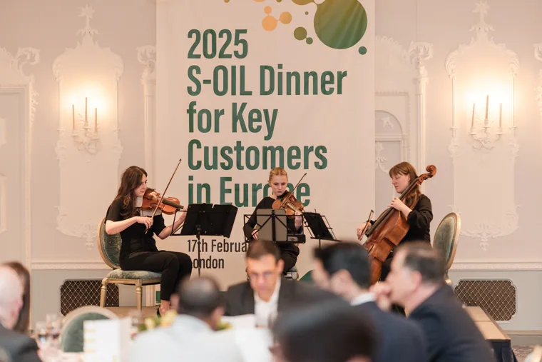 Musicians performing in front of the event sign at the S-OIL European customer dinner.