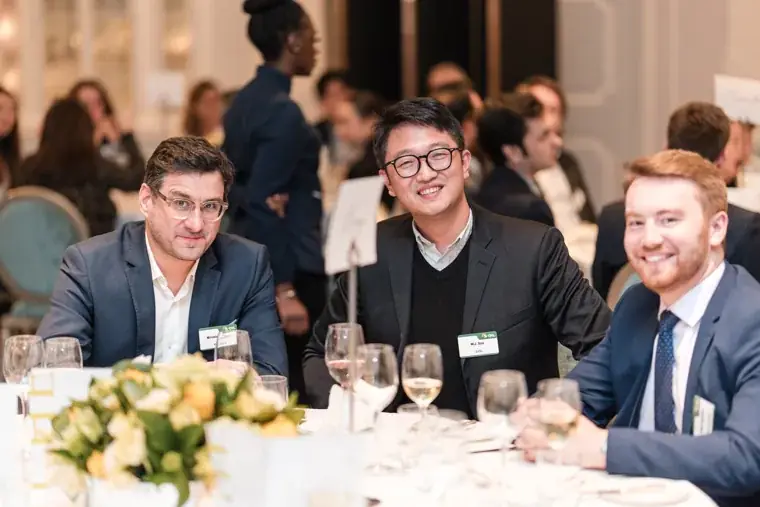 Three guests posing at a dining table at the S-OIL European customer dinner.