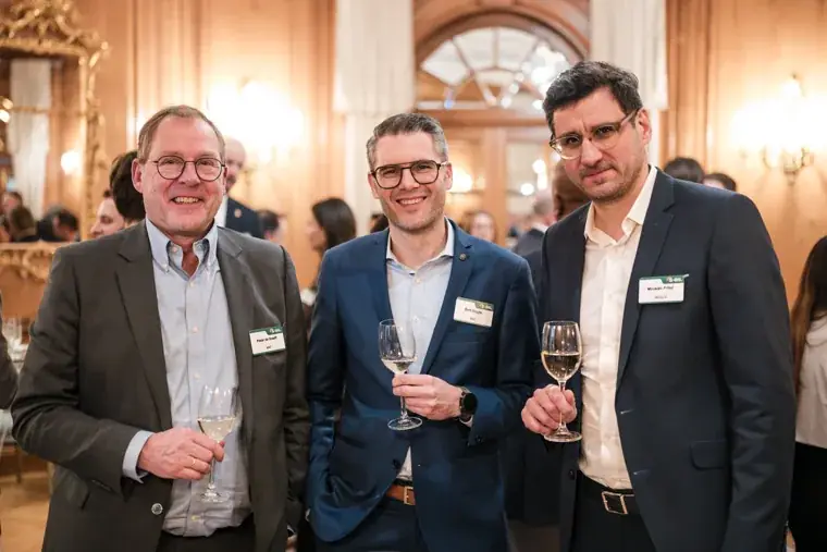 Three guests posing together with drinks at the S-OIL European customer dinner.