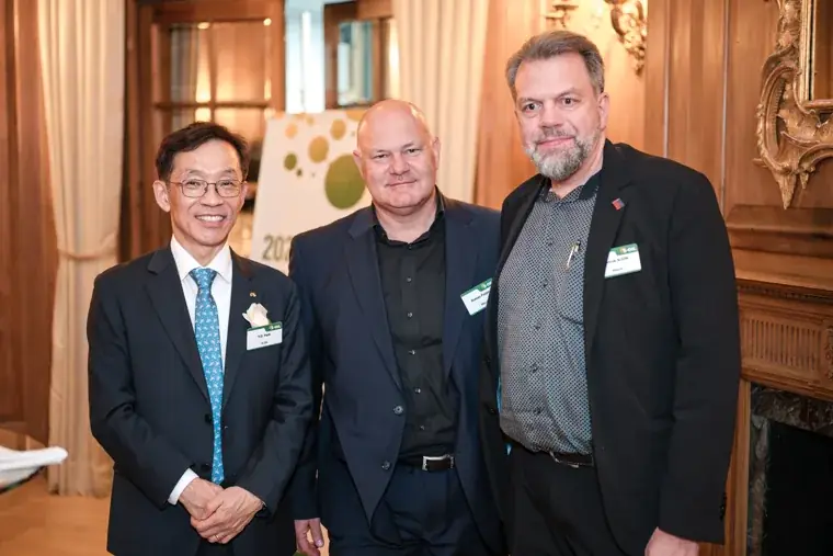 Three guests posing with drinks at the S-OIL European customer dinner.
