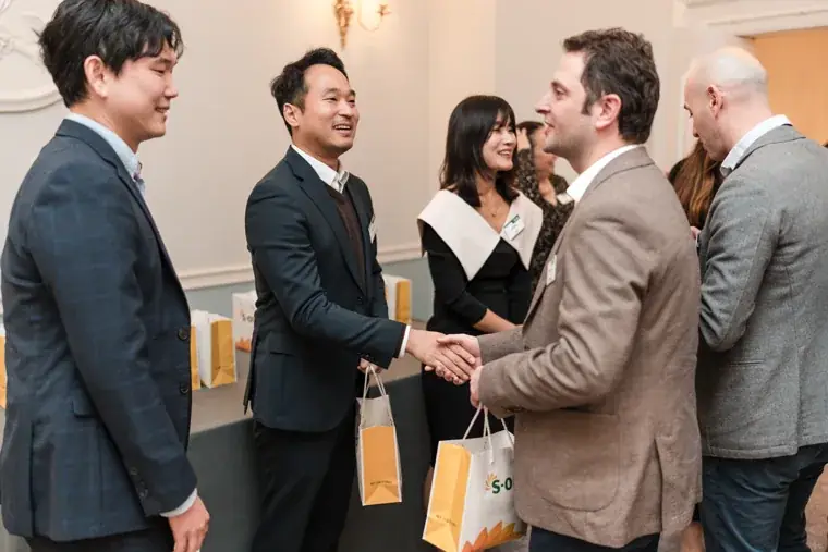 Two guests shaking hands at the reception at the S-OIL European customer dinner.