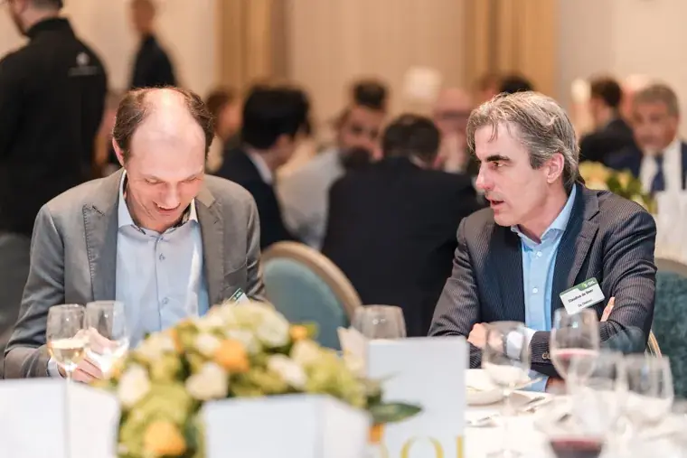 Two guests talking across a floral table centrepiece at the S-OIL European customer dinner.