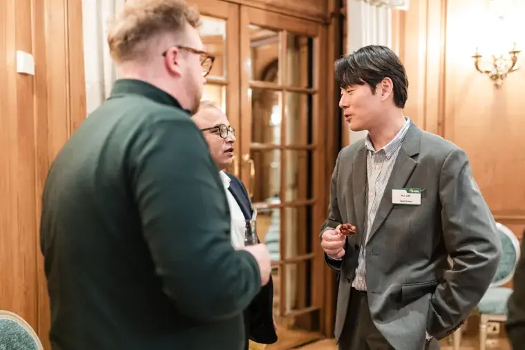 Two guests talking beside the wood-panelled doorway at the S-OIL European customer dinner.