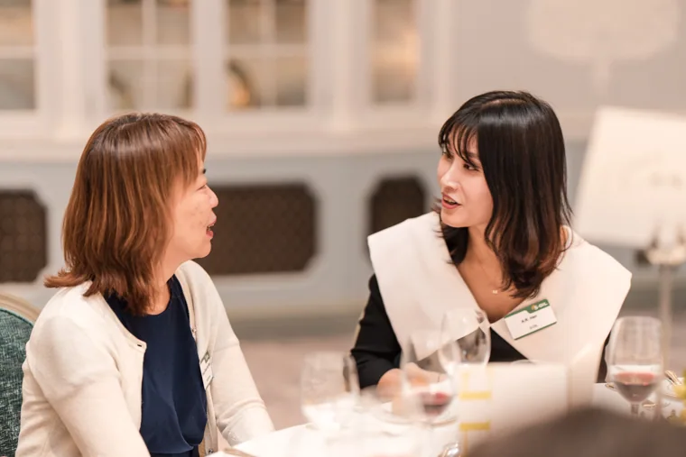Two women talking face to face at dinner at the S-OIL European customer dinner.